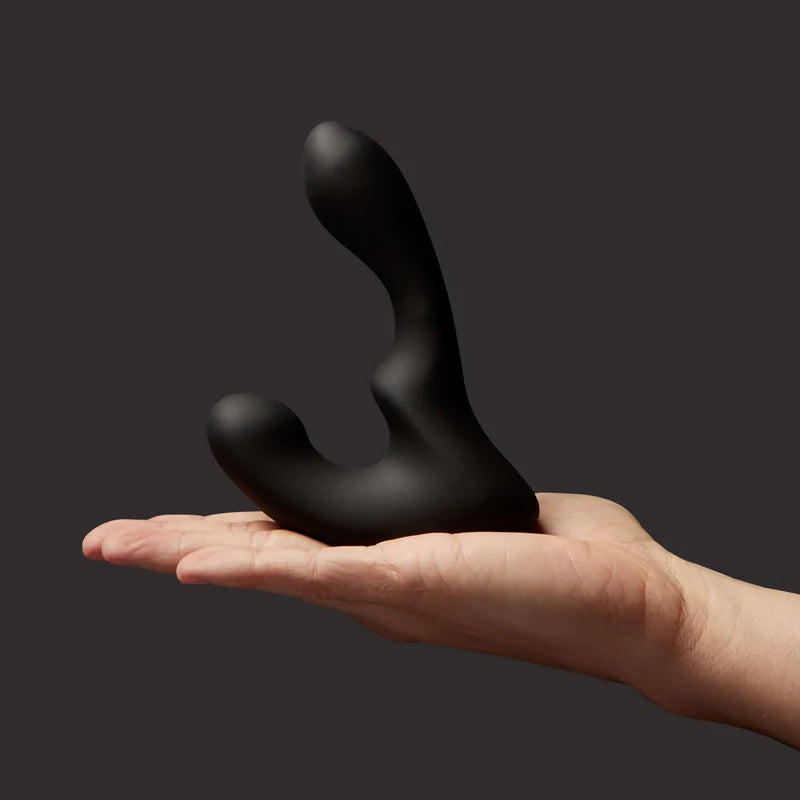 giddi tomo massager held in a hand against a dark background