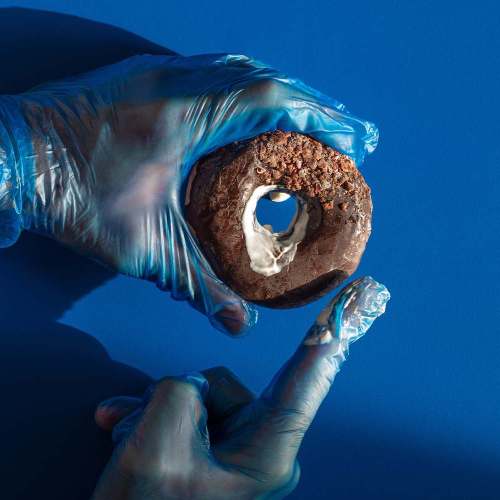 Man holding a chocolate donut that represents a rectum